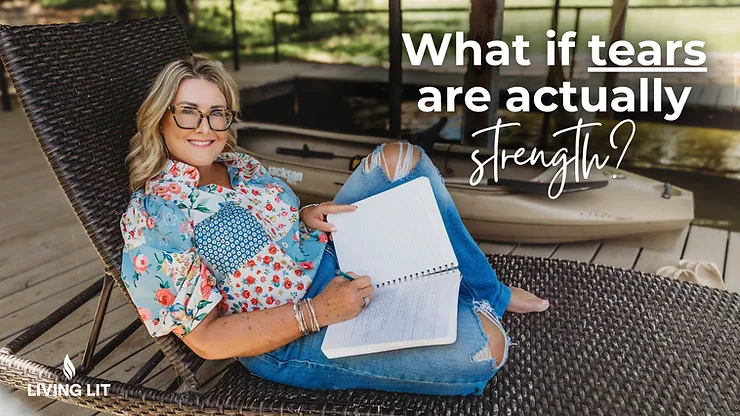 Michelle sitting in a patio chair waring a flowered shirt and blue jeans while writing in her journal and smiling at the camera.