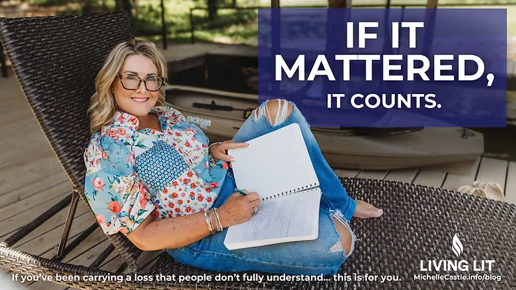 Photo of Michelle in a wicker chair smiling at the camera and writing in her journal. She's wearing a floral shirt, glasses, and blue jeans with holes in the knee. 