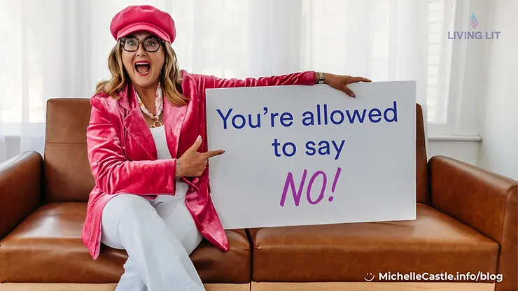 Michelle sits in pink hat and jacket on a brown leather couch and points to a sign reading You’re allowed to say NO!